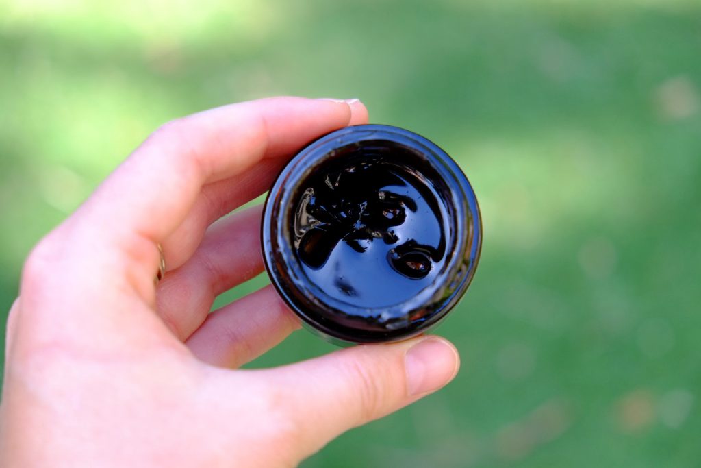 Pot de Shilajit ouvert, fond nature et lumière